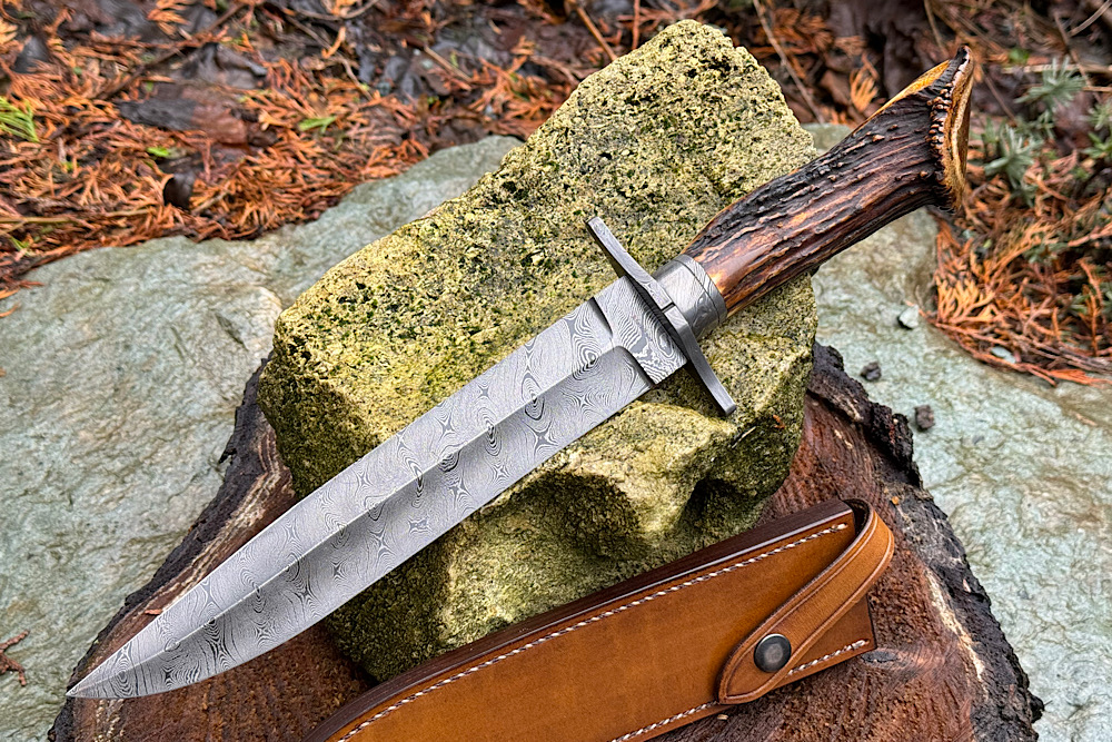 Schmidbauer Fighter Grizzly Klingenlänge 216 mm, Klingenstärke 5 mm, Damast Messerwerk tordiert. 360 Lagen. Beschlag Messerwerk Damast. Griff feinstes Sambar Hirschhorn in sehr selten schöner Farbe.Gesamtlänge 358 mm. 